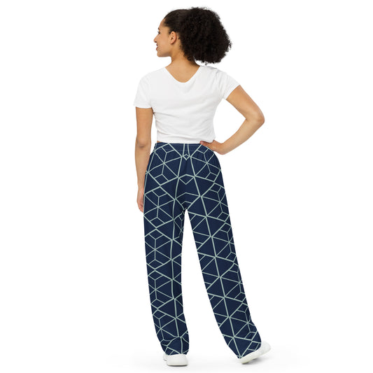 Woman wearing a white top and blue geometric patterned pants on a white background