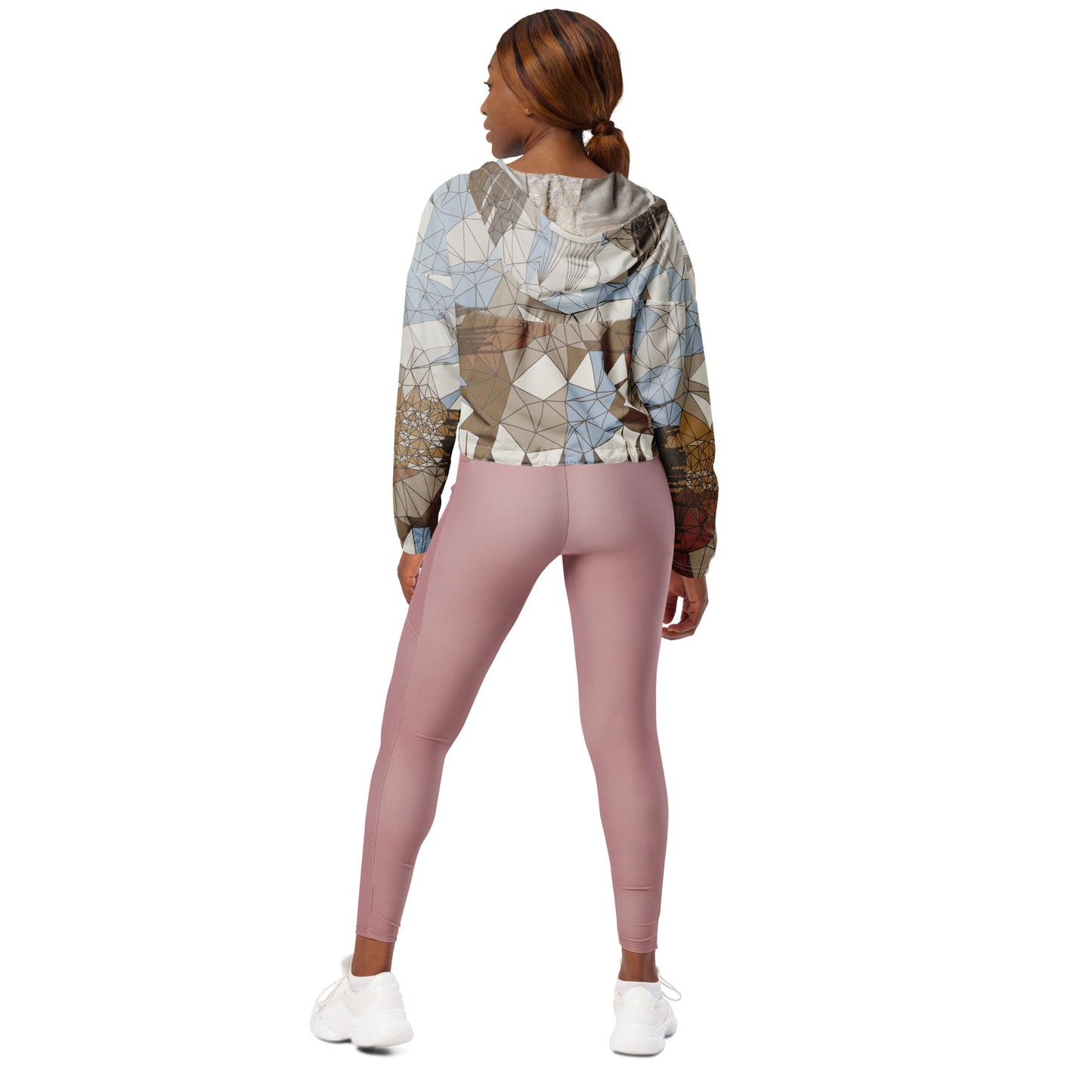 Woman wearing a patterned windbreaker and pink leggings on a white background