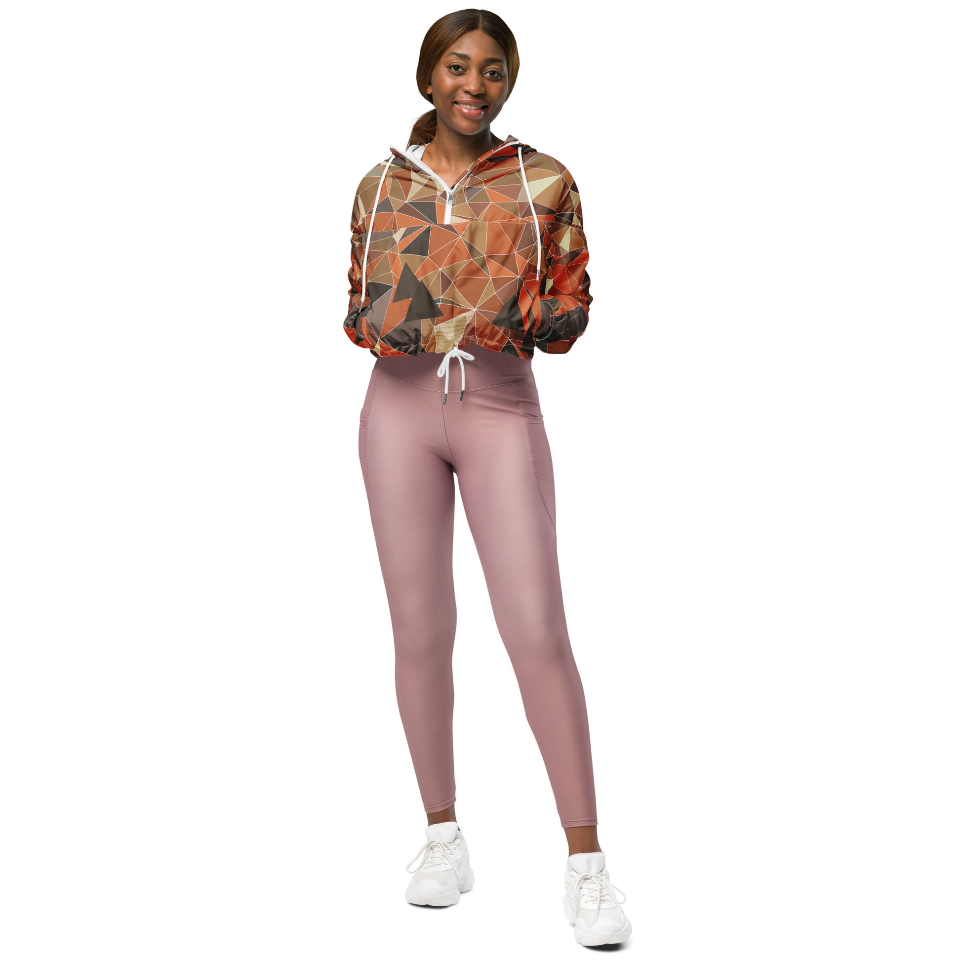 Woman wearing a cropped multicolor geometric patterned windbreaker jacket and pink leggings on a white background