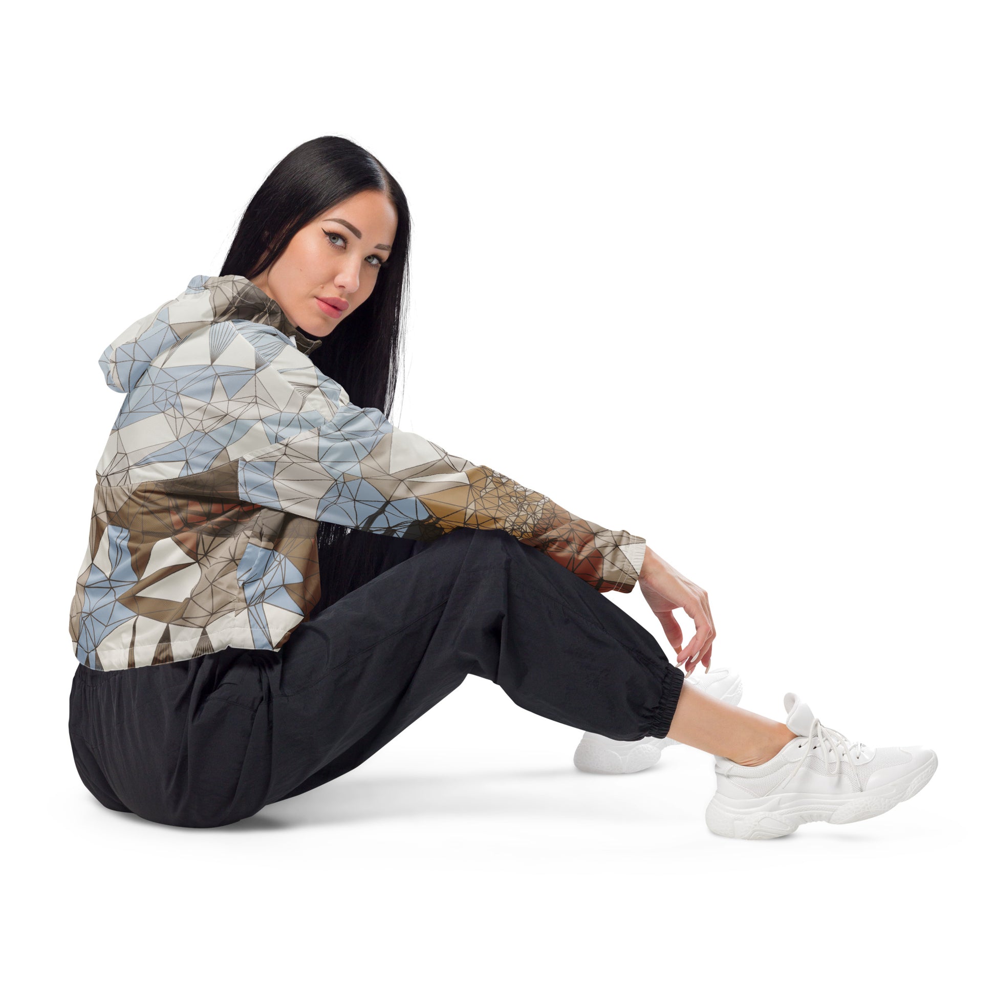 Woman wearing a geometric patterned windbreaker and black pants on a white background