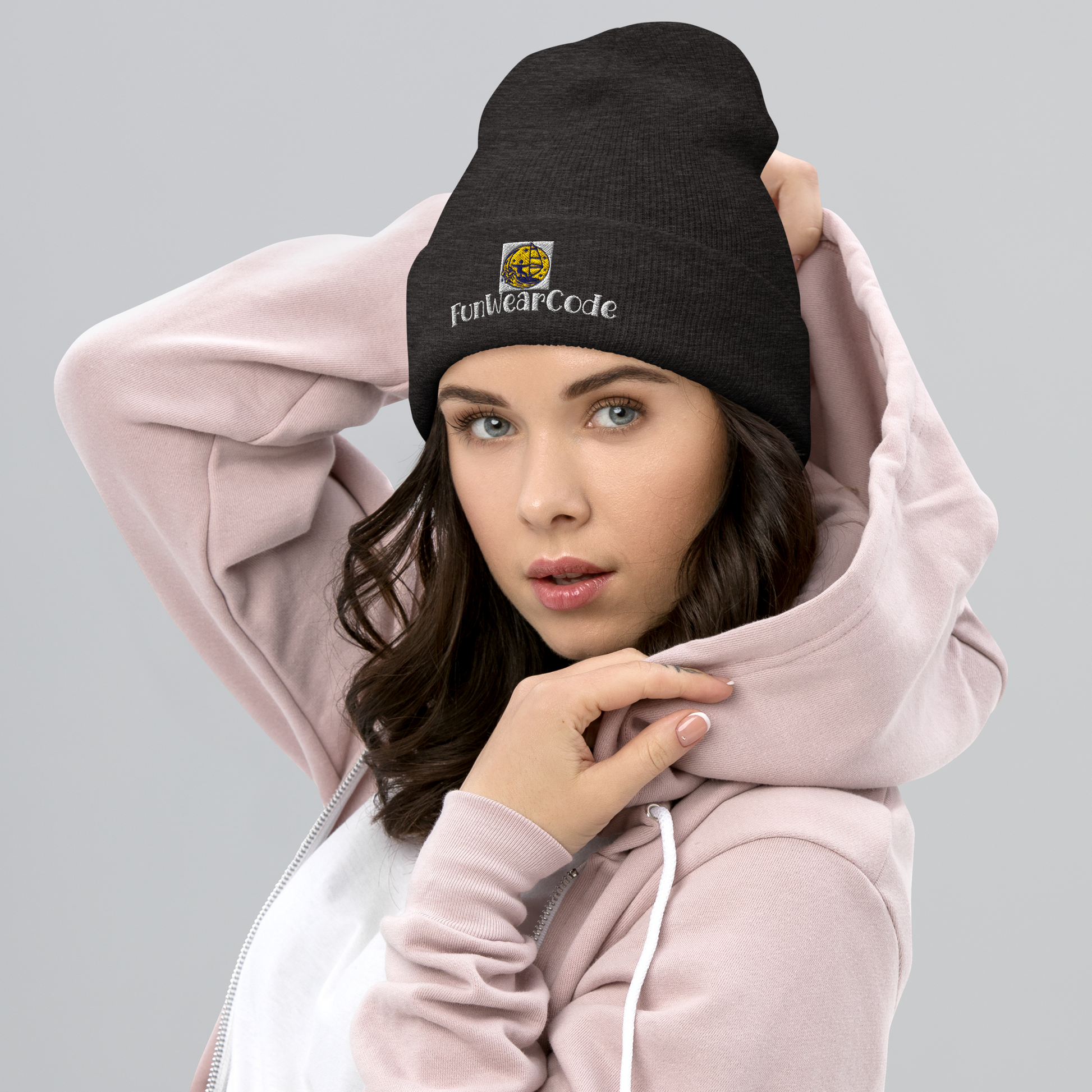 Woman wearing a black beanie with a FunWearCode logo and a pink hoodie on a gray background